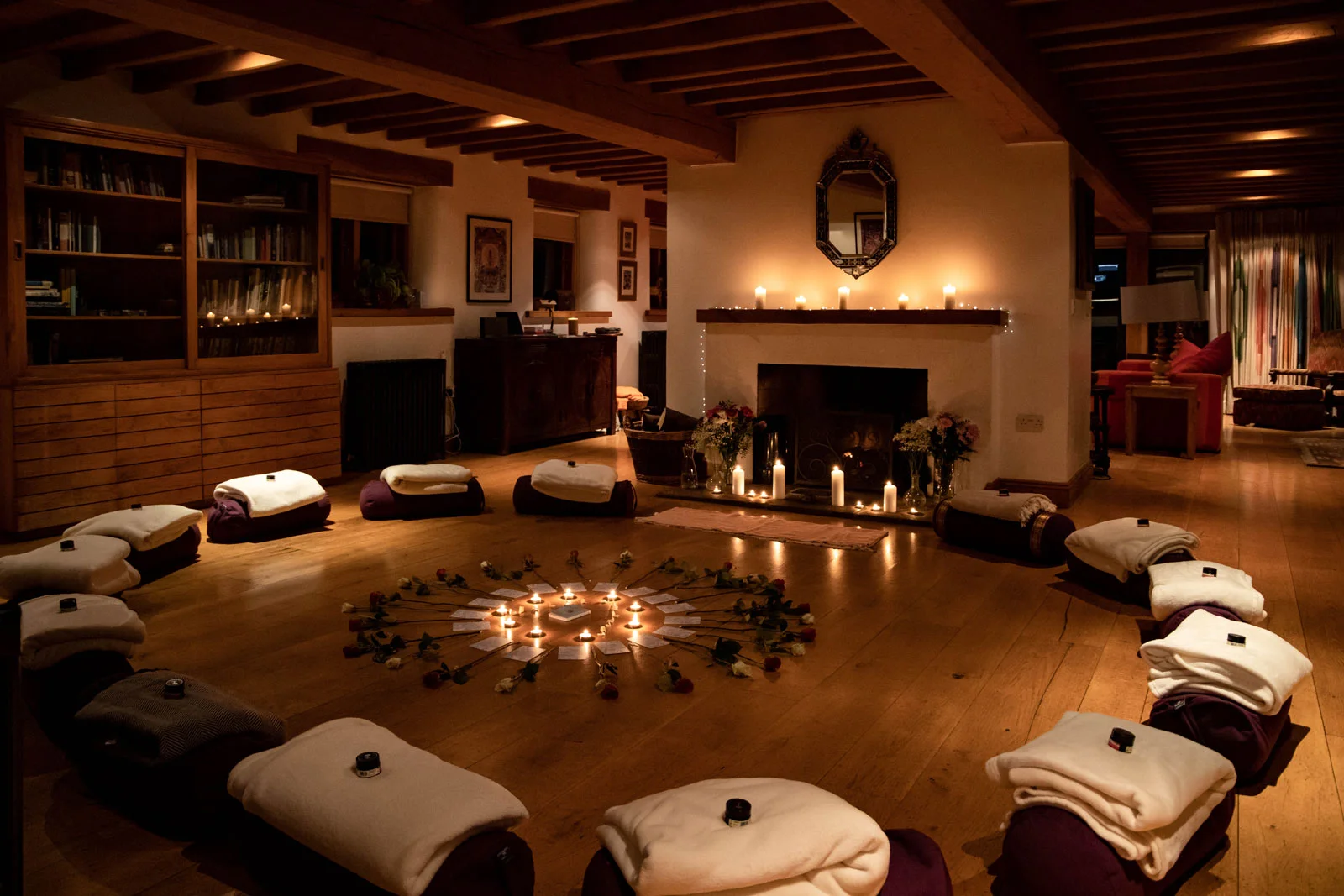 Candlelit retreat meditation room with cushions around a fireplace