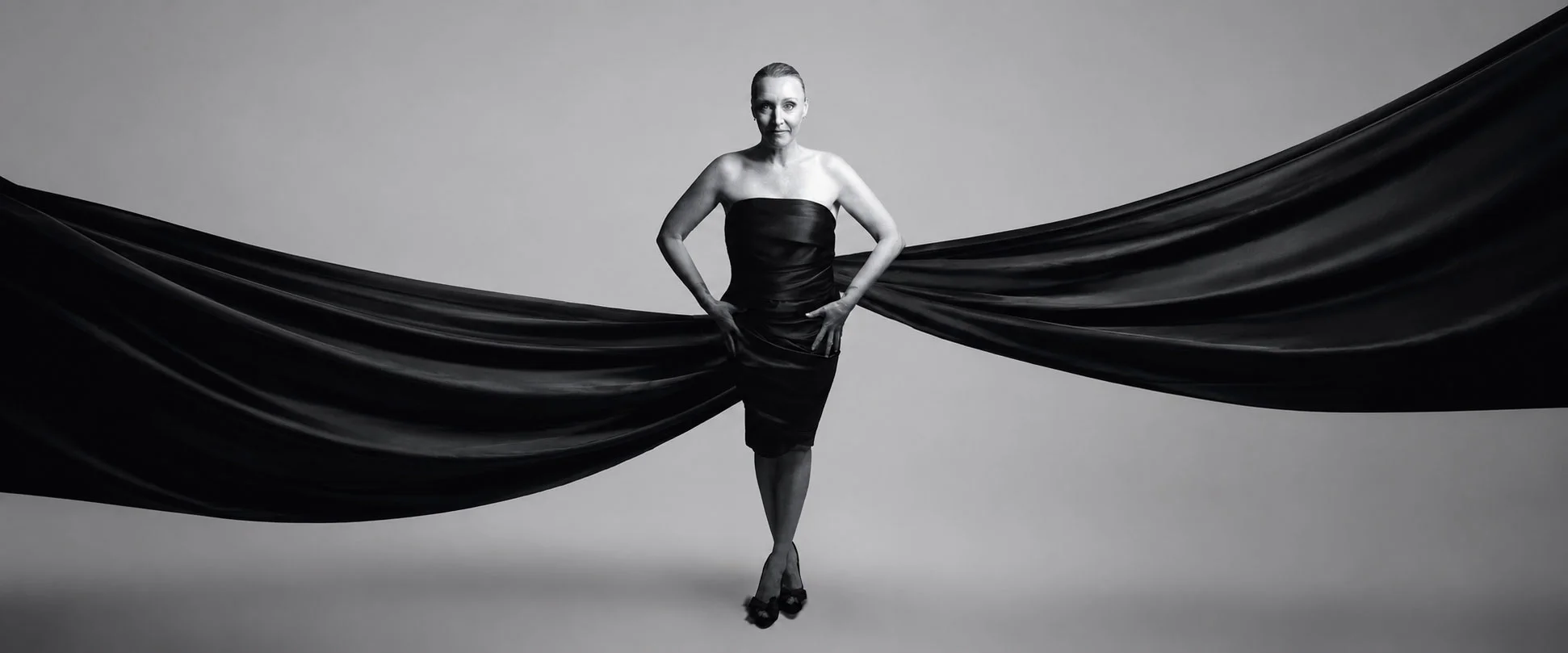 Woman in a black dress framed by flowing fabric